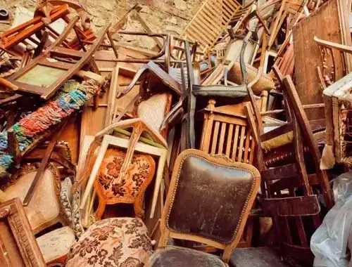Dachboden voller gestapelter Holzstühle und alter Polstermöbel